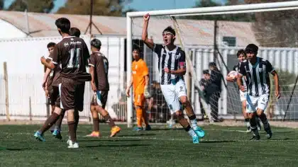 Jugador saltando para conectar un centro en los minutos finales del partido, con la multitud de fondo en el estadio