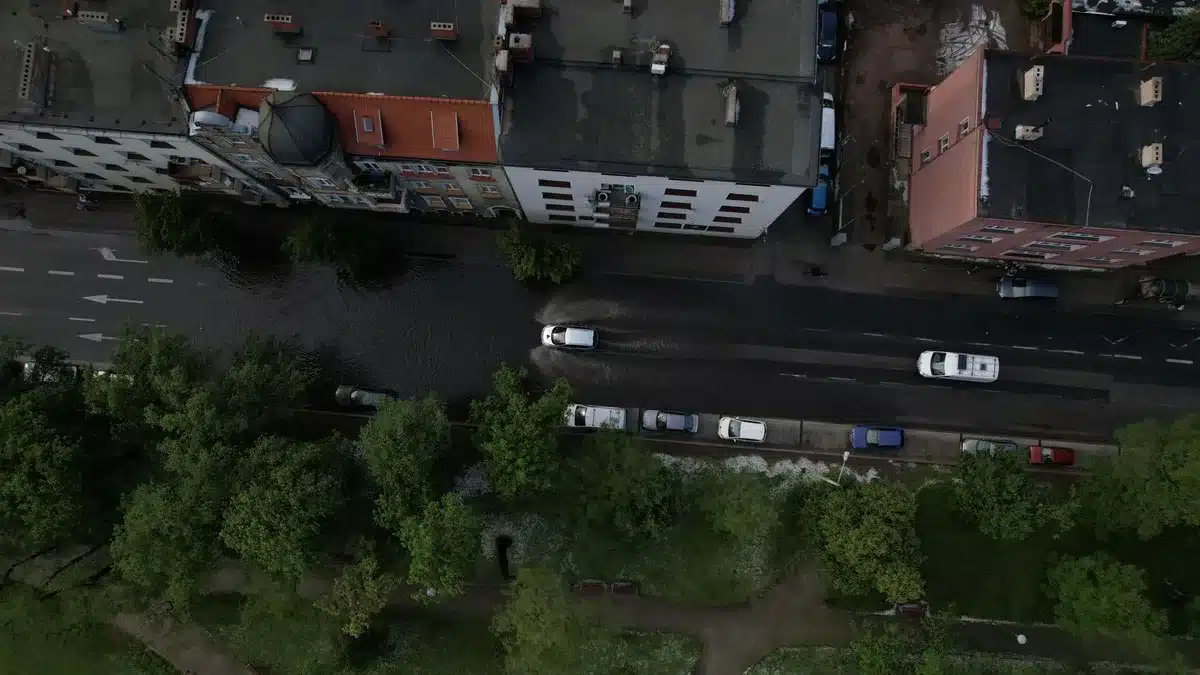 Calle inundada con agua en edificios, barreras de emergencia y residentes observando
