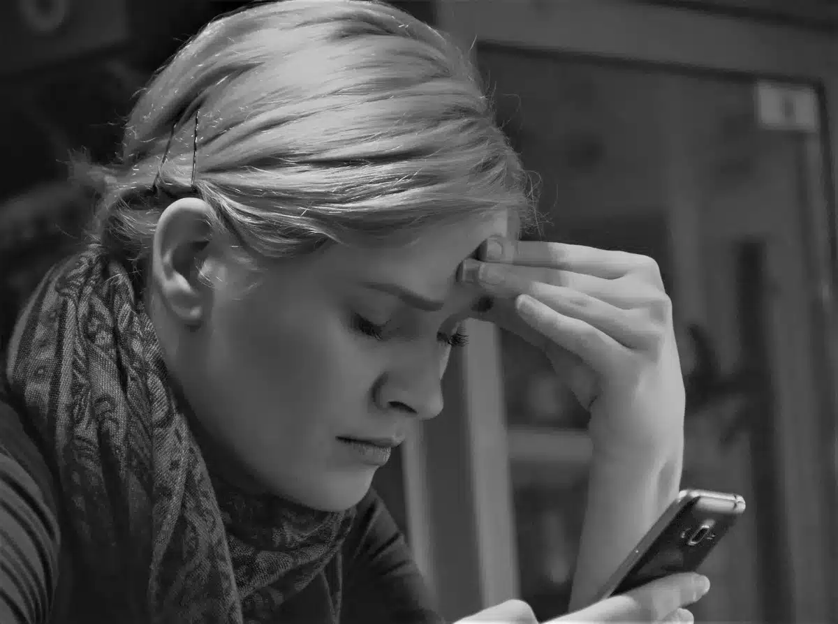 Manos sosteniendo un teléfono móvil con redes sociales, simbolizando la saturación de pantallas
