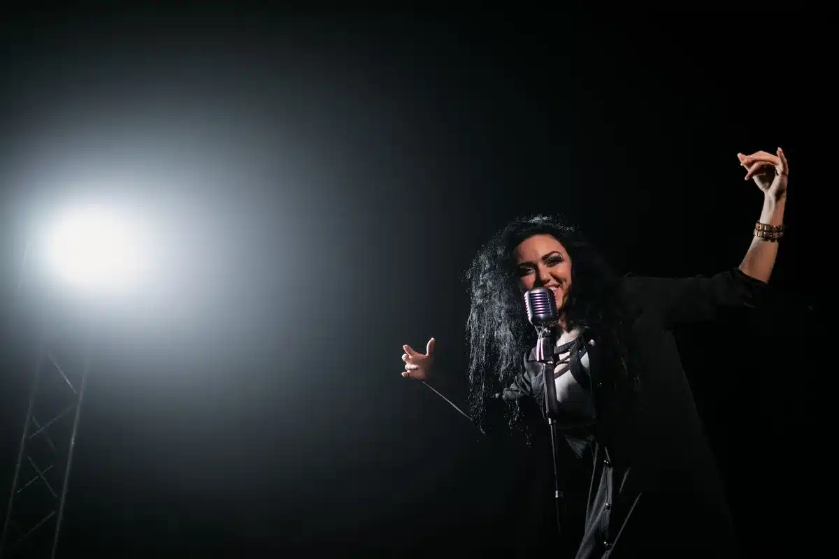 Cantante en un escenario íntimo con iluminación cálida durante un concierto