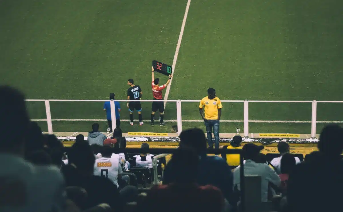 Jugador joven ingresando al campo desde el banquillo en estadio iluminado