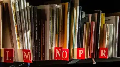 Persona leyendo un libro abierto en una librería con estantes de fondo