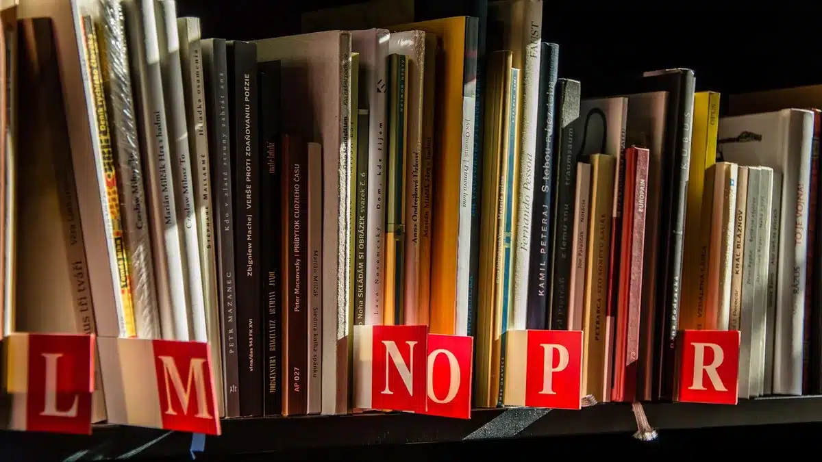 Persona leyendo un libro abierto en una librería con estantes de fondo