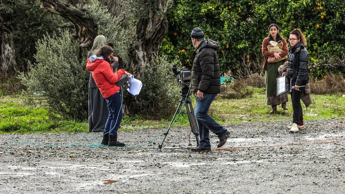 Equipo de filmación trabajando en un paraje rural con cámara y funcionarios