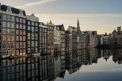 Pareja caminando abrazada por una calle con arquitectura europea y canal de fondo
