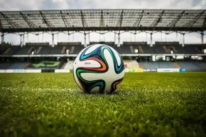 Estadio de fútbol lleno con afición animando durante un partido de Premier League
