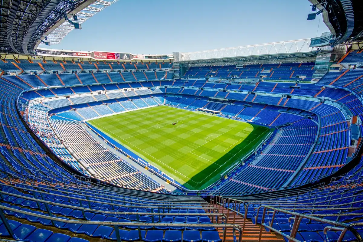 Manos de hinchas anónimos en la tribuna con la cancha al fondo