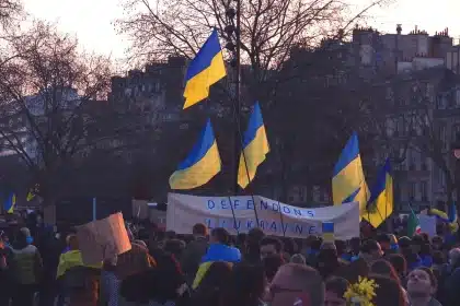 Multitud anónima en marcha con pañuelos verdes y violetas y banderas