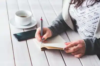 Manos sobre una libreta y un mapa en una mesa de conferencia con micrófonos al fondo