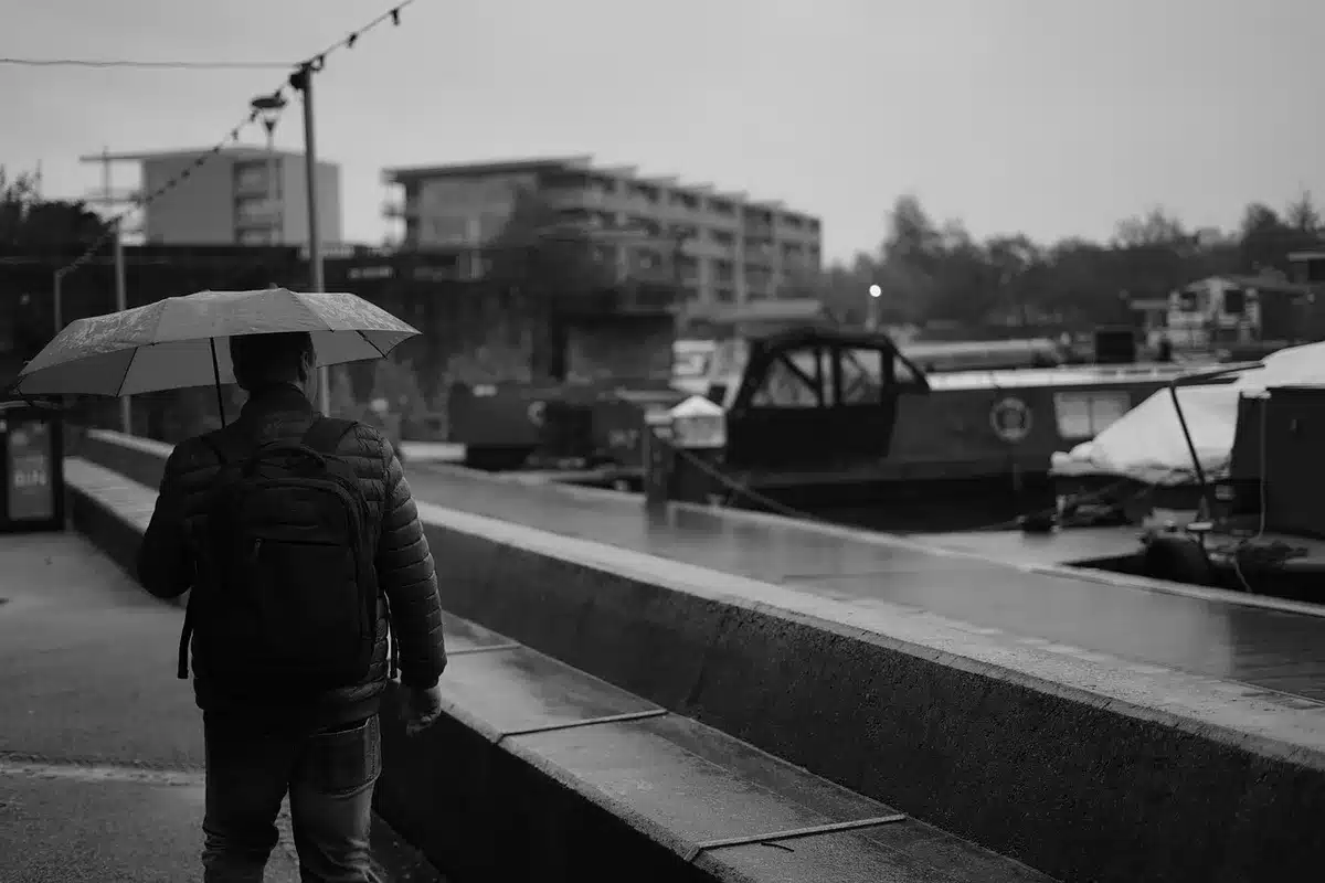 Joven peregrina con capa plástica avanzando bajo la lluvia hacia la basílica